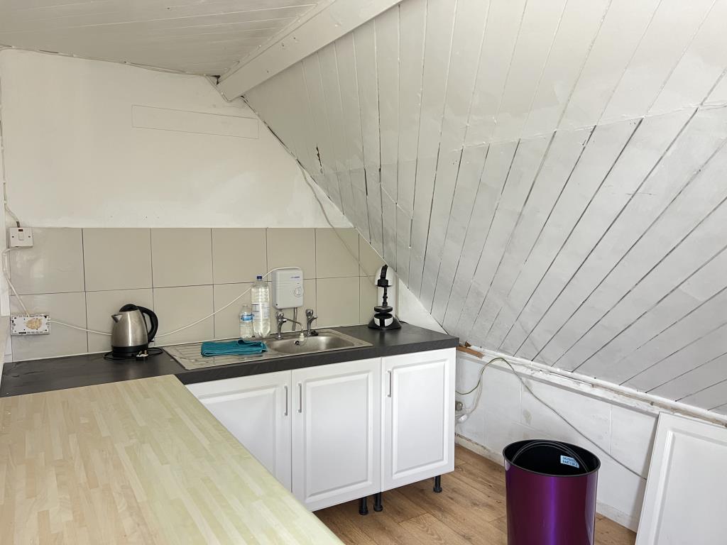 Lot: 3 - FREEHOLD COMMERCIAL INVESTMENT WITH RESIDENTIAL CONVERSION POTENTIAL - Kitchen area with cupboard units and sloped ceilings